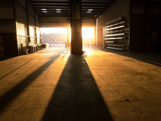 velké prázdné skladiště, otevřená vrata, východ slunce, jak svítí do prostoru